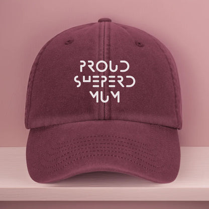 Vintage-style burgundy baseball cap with white embroidery that reads "Proud Shepherd Mum" in a bold modern font. Designed as a personalised gift for German Shepherd dog mums and proud dog parents.